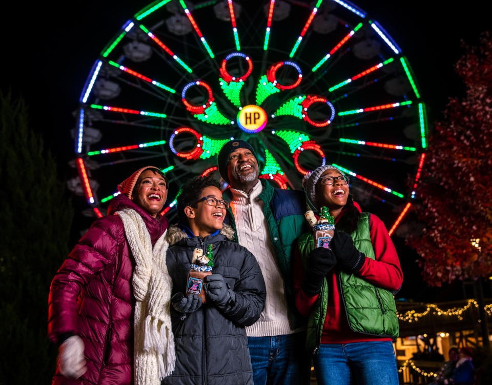 Christmas lights reflecting off the stream with rides lining both sides