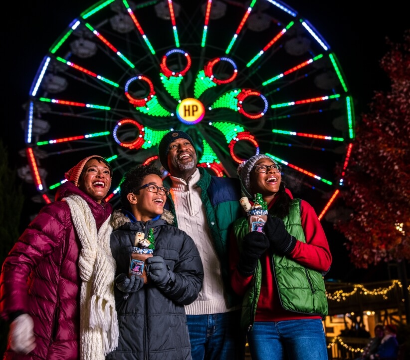 Happy family in front of ferris wheel at Hershheypark Christmas Candylane